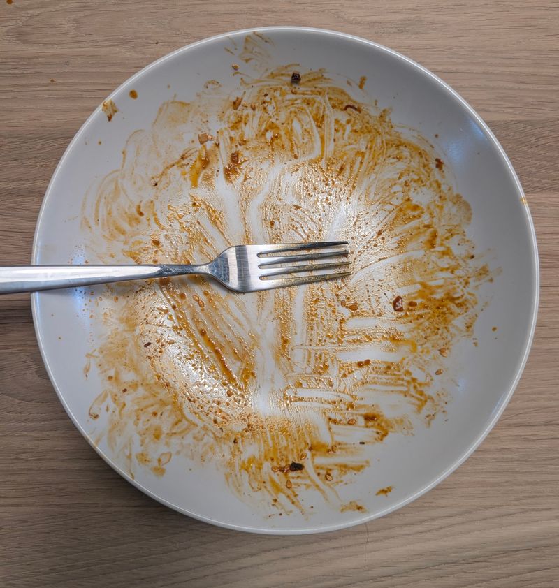 Fertig gekochte, gut vermischte Nudeln mit brauner Soße in einer weißen Schüssel von oben